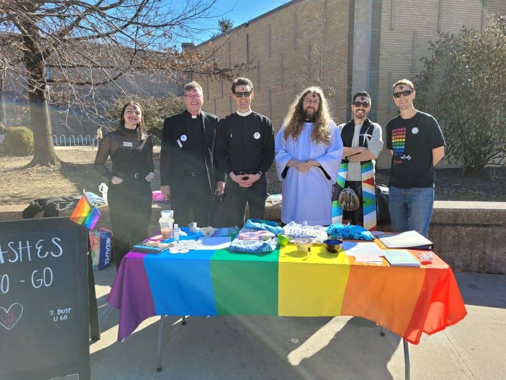 Group of people at Pride event outside Calvary Episcopal Church with rainbow tablecloth.