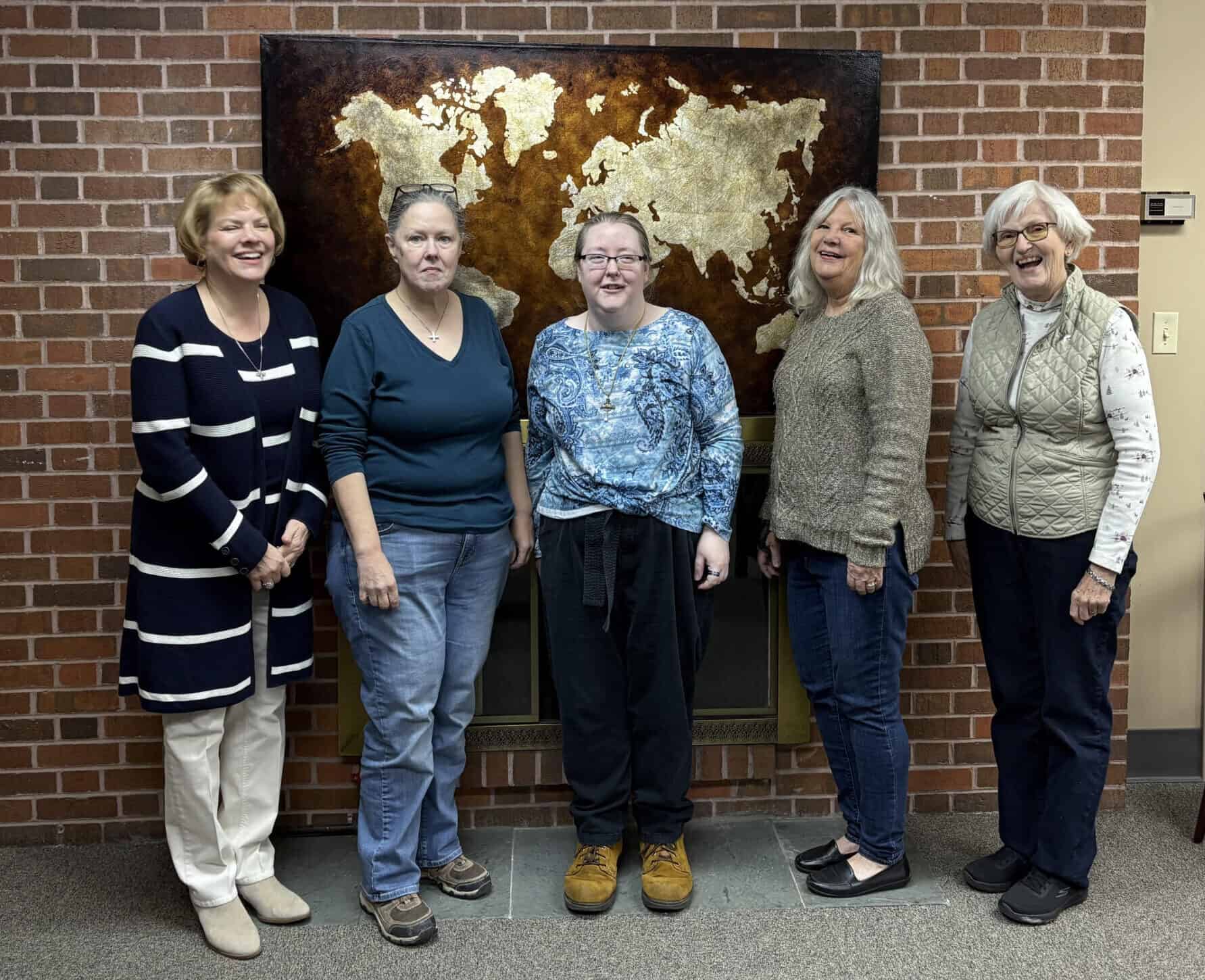 Group of women standing inside Calvary Episcopal Church with world map artwork.