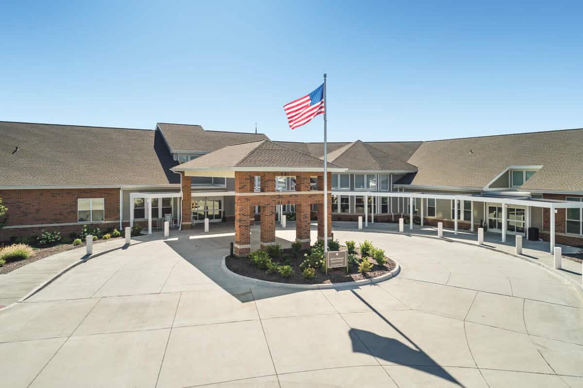 Lenoir Woods exterior building with American flag and welcoming entrance.