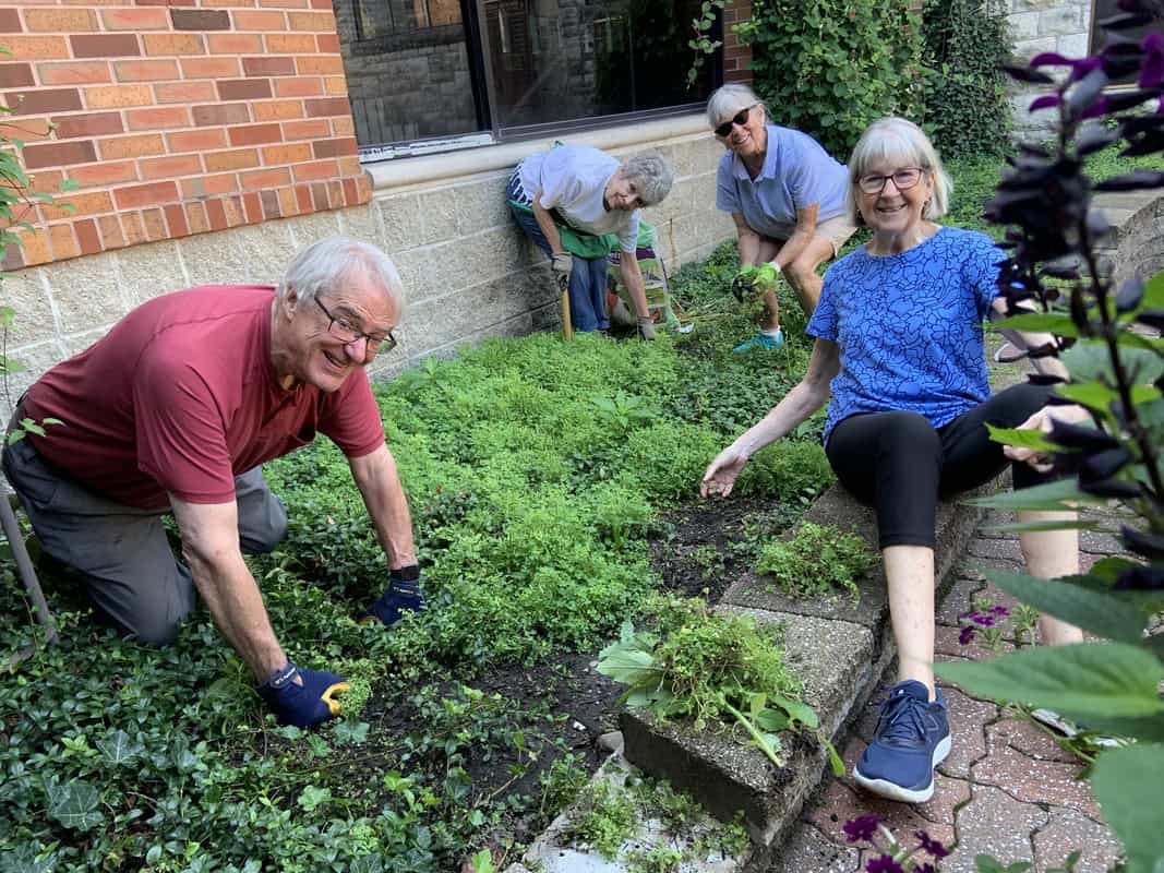 Elderly volunteers gardening outside Calvary Episcopal Church building.